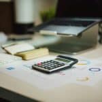 Bureau de gestionnaire de paie avec calculatrice et tableaux chiffrés pour le calcul des cotisations sociales